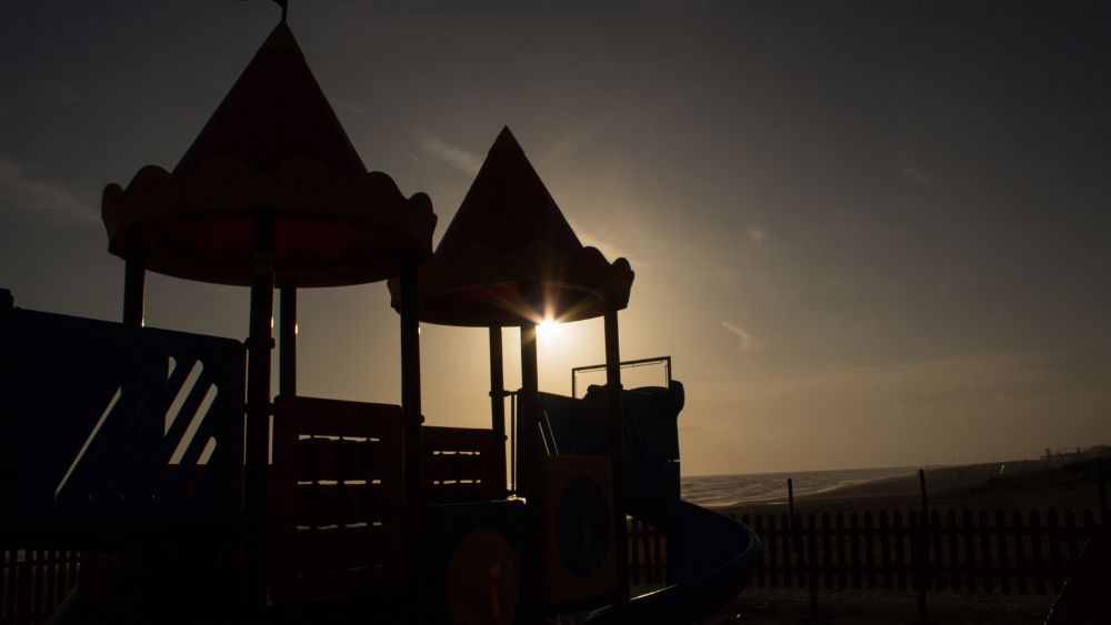 "Quest'immagine cattura la tranquilla bellezza di un parco giochi al primo raggio di sole, dove i colori vivaci delle attrezzature ludiche si stagliano contro il cielo dell'alba. Questo momento sereno sottolinea l'importanza dei parchi giochi progettati secondo criteri ambientali minimi, offrendo uno spazio sicuro e stimolante per i bambini in un contesto naturale e sostenibile. L'alba sul parco giochi simboleggia un nuovo inizio, ricordandoci la necessità di spazi ludici che rispettino e valorizzino l'ambiente circostante, promuovendo la salute del nostro pianeta per le future generazioni di bambini e famiglie.