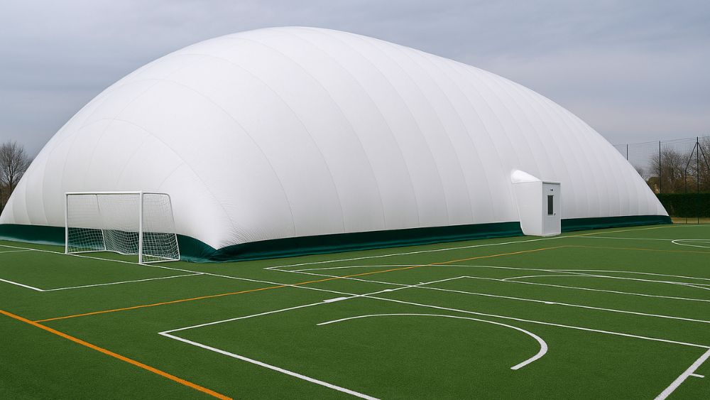 Struttura pressostatica bianca su campo sportivo in erba sintetica, perfetta per campi coperti. L’immagine mostra una copertura pressostatica per campi sportivi, utilizzata nella realizzazione di campi sportivi indoor, come calcetto o multisport. La tensostruttura per campi sportivi assicura protezione da agenti atmosferici, ventilazione naturale e massima funzionalità per ogni stagione. Ideale per chi cerca una struttura coperta per campi sportivi efficiente e moderna.
