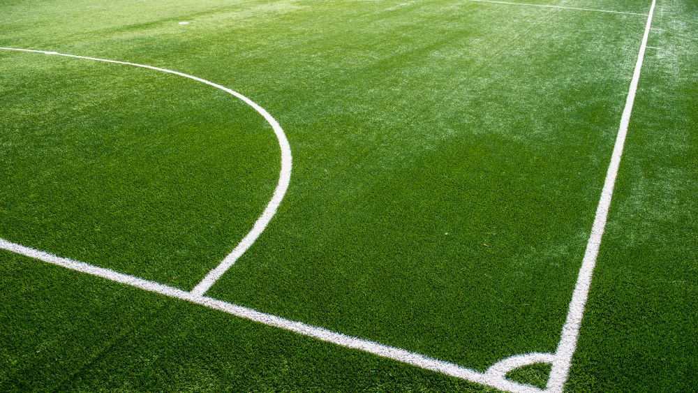 Vista panoramica di un campo da calcetto in erba sintetica, con illuminazione professionale e recinzione. Green Power Service realizza campi da calcetto a Bologna, Firenze, Prato e in tutta Emilia-Romagna e Toscana, offrendo soluzioni complete e servizi di manutenzione specializzata.