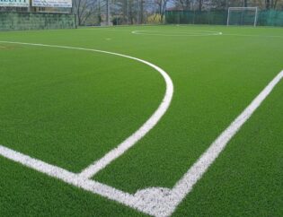 Dettaglio del nuovo manto in erba sintetica dopo il rifacimento di un campo da calcetto, con superficie uniforme, linee di gioco e sistema prestazionale per il calcio a 5.