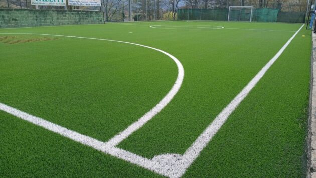 Dettaglio del nuovo manto in erba sintetica dopo il rifacimento di un campo da calcetto, con superficie uniforme, linee di gioco e sistema prestazionale per il calcio a 5.