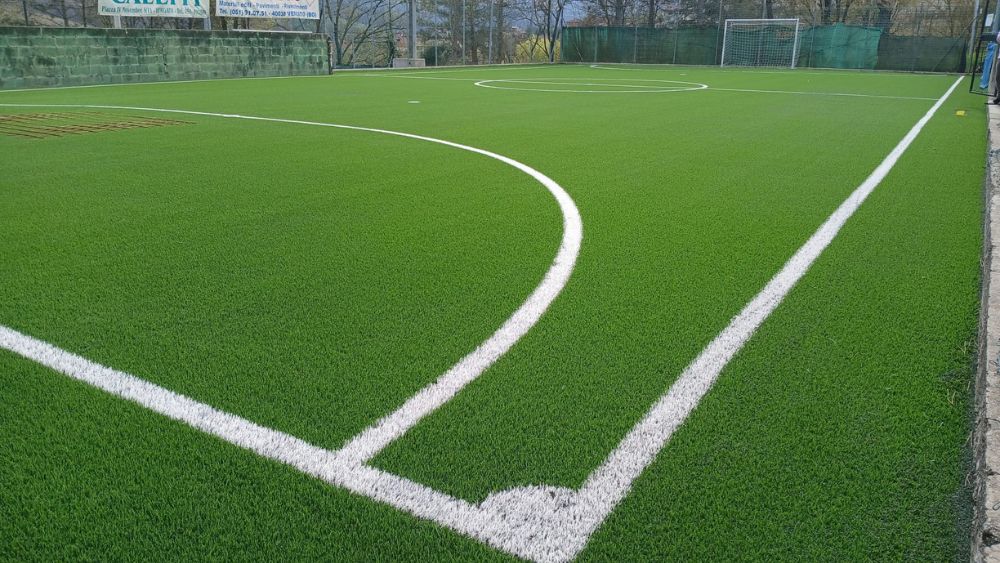 Dettaglio del nuovo manto in erba sintetica dopo il rifacimento di un campo da calcetto, con superficie uniforme, linee di gioco e sistema prestazionale per il calcio a 5.
