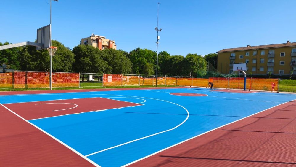 Pavimentazione campo da basket esterno realizzata con resina acrilica sportiva bicolore, nuova superficie outdoor progettata per garantire uniformità e resistenza.
